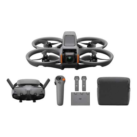 Compact FPV drone with propeller guards and camera hovering low over a grassy field